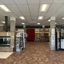 Interior of a store with tile displays, red brick flooring, and overhead lighting.