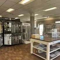 Interior of a lumber supply store. Shelves of wood are displayed, with a large counter in the foreground.