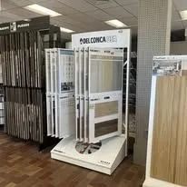 A display of Del Conca tile samples in a store. White, vertical panels show various colors and textures.