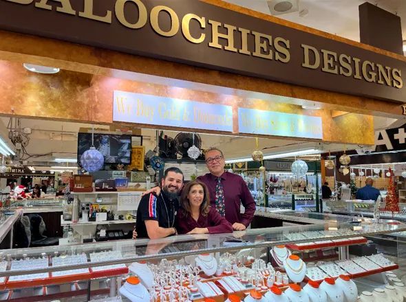 A group of people standing in front of a store called baloochies designs.