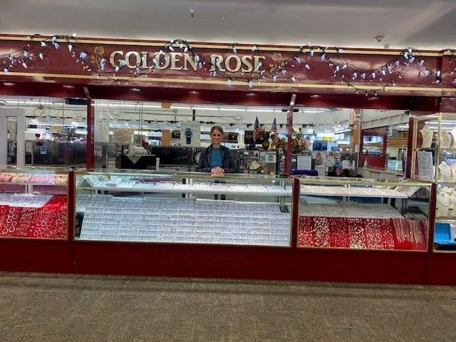 A man is standing in front of a store called golden rose