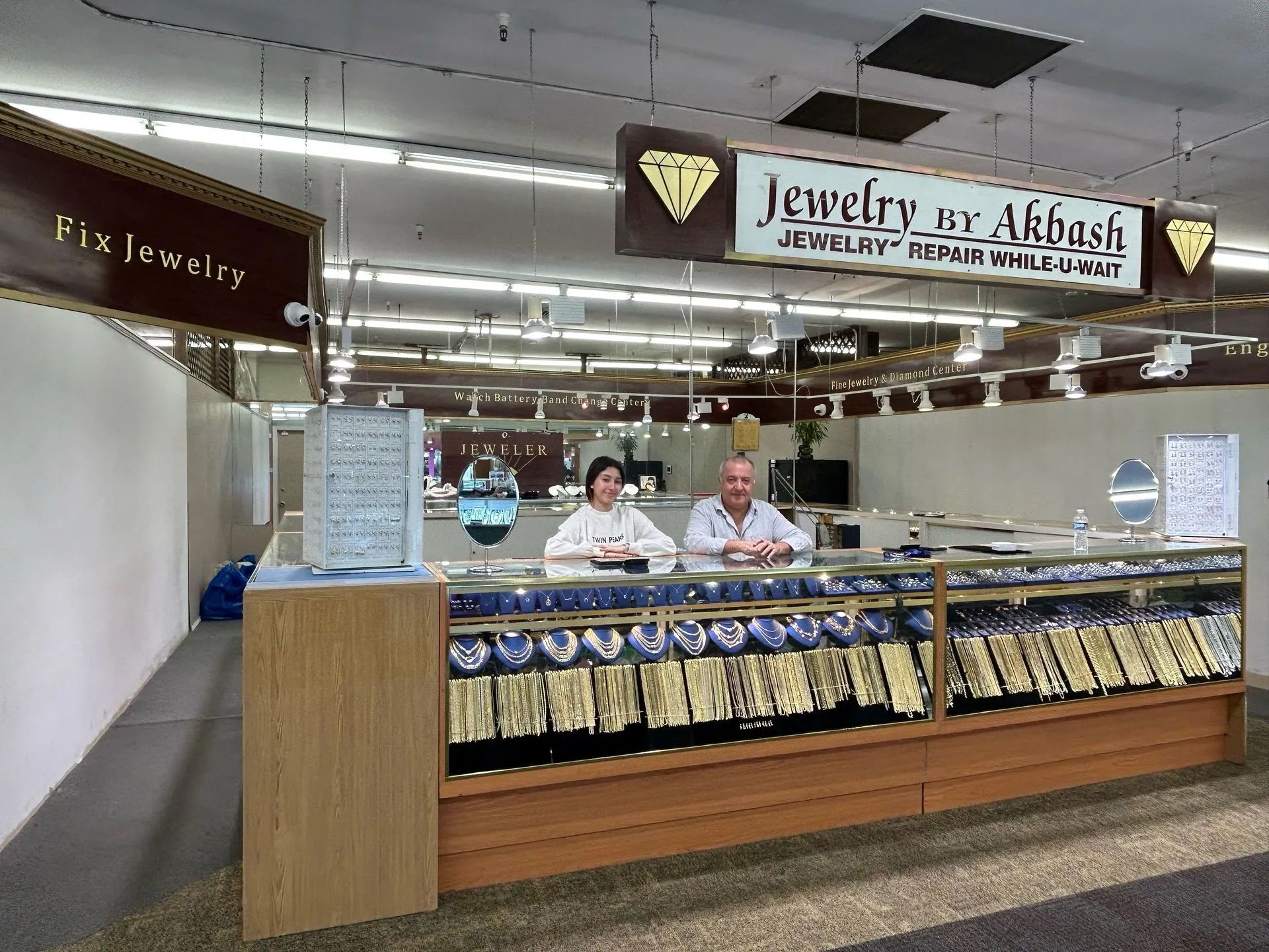 A man and a woman are behind the counter of a jewelry store.