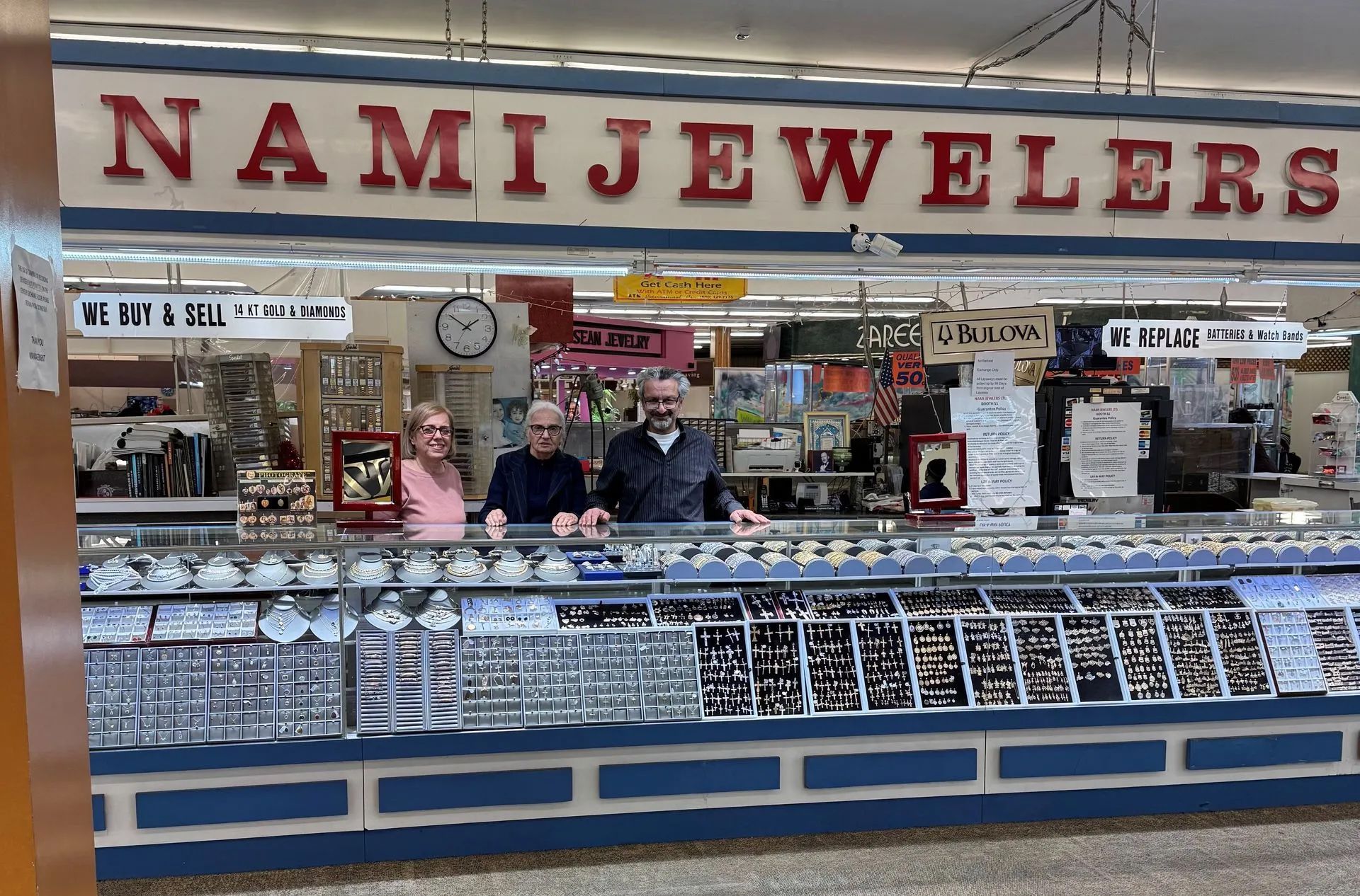 A man and woman are standing in front of a nami jewelers store.