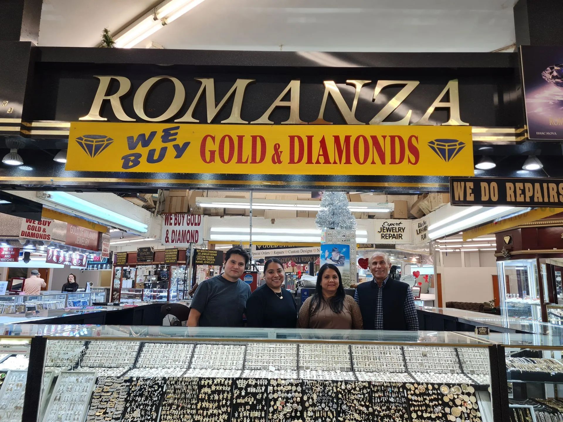 A group of people standing in front of romanza we buy gold and diamonds.