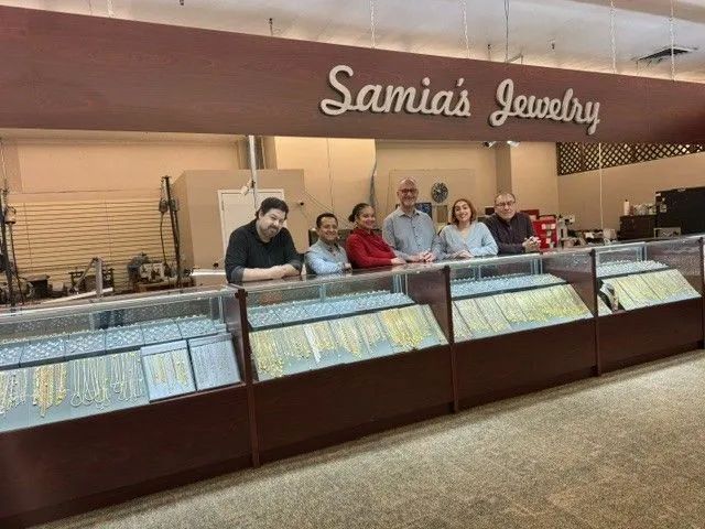 A group of people are standing in front of a display case in a jewelry store.