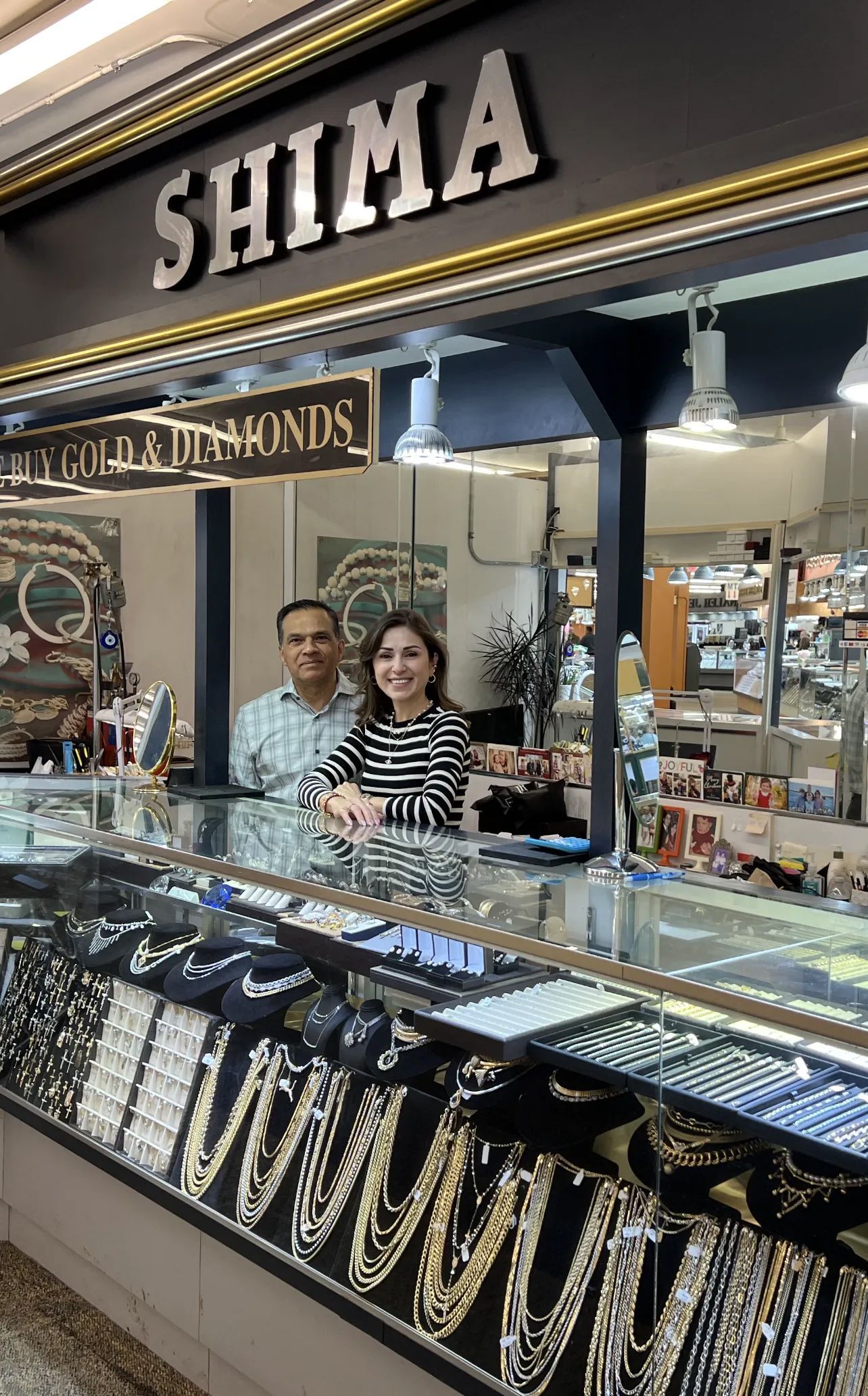 A man and a woman are standing behind a counter in a jewelry store.