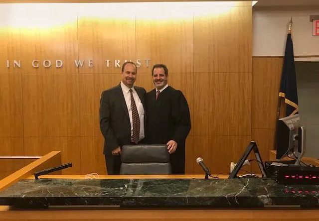 Two men are standing next to each other in a courtroom.