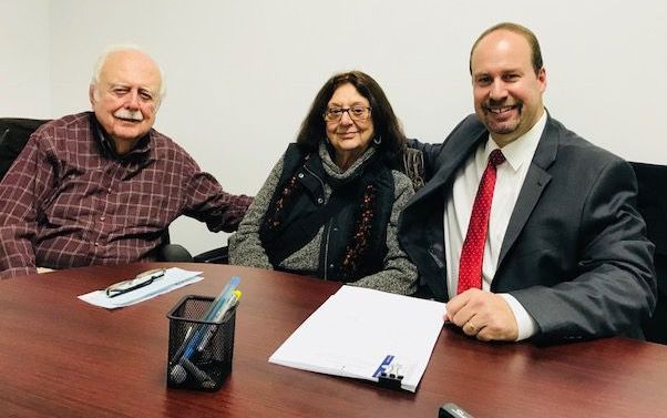 A man in a suit and tie is sitting at a table with two other people.