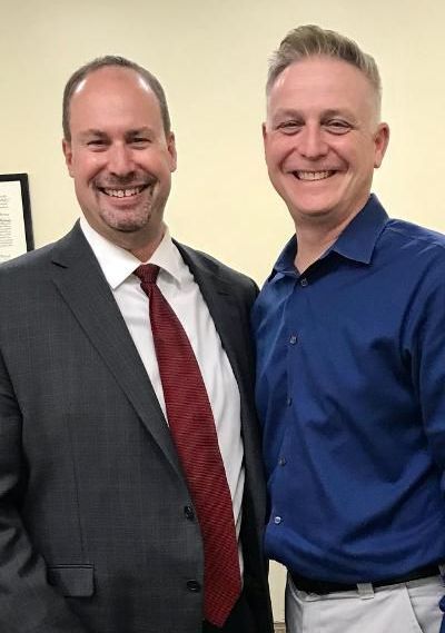 Two men in suits and ties are posing for a picture.