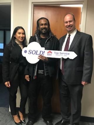 A man is holding a key that says sold on it