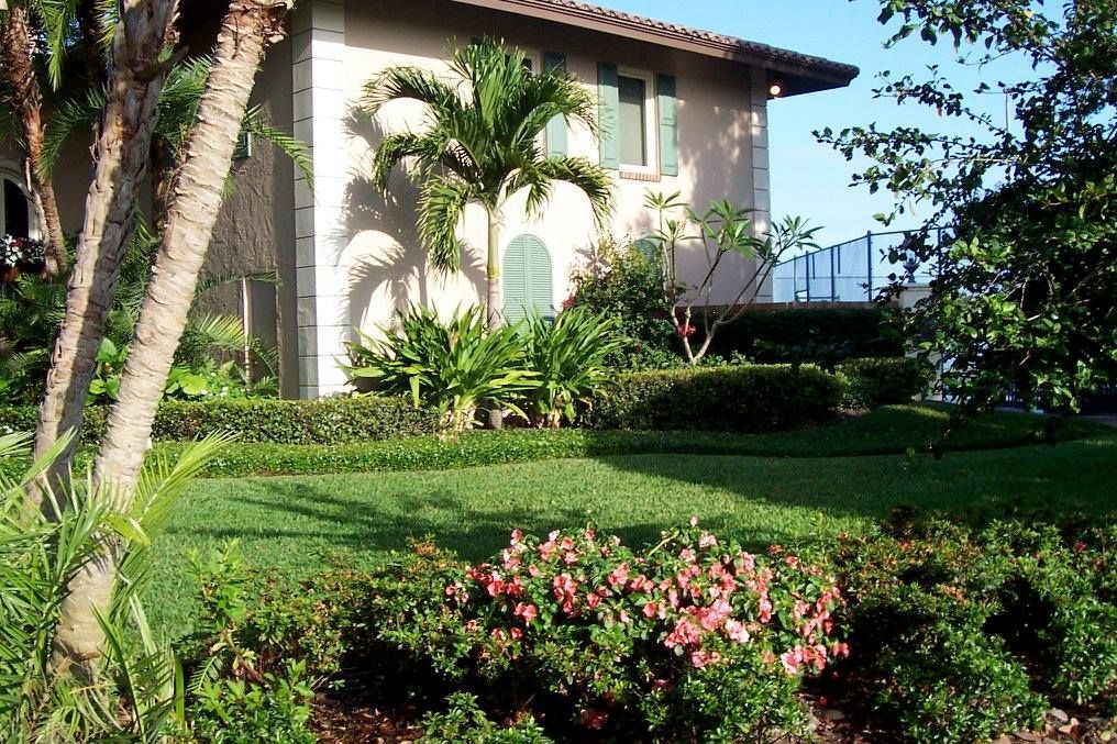 A house with a lush green lawn and flowers in front of it