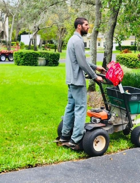 A man is pushing a lawn mower down a road