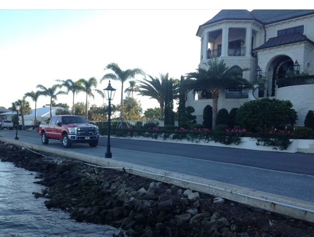 A red truck is parked in front of a large white house