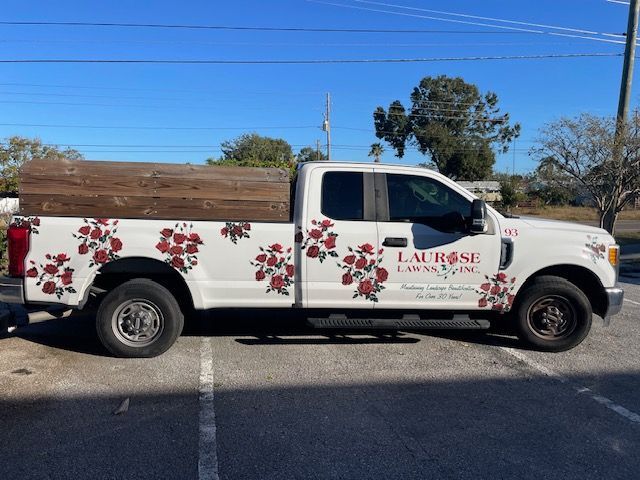 A white truck with red roses on the side is parked in a parking lot.