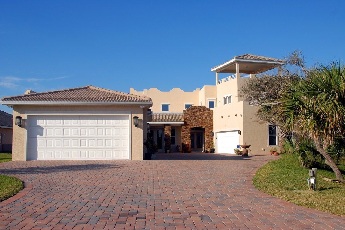 A large house with two garage doors and a brick driveway