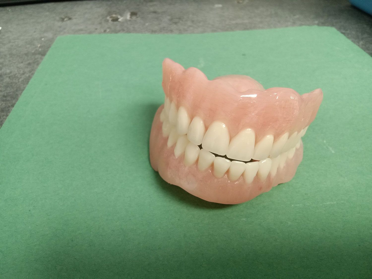 A close up of a denture on a green surface