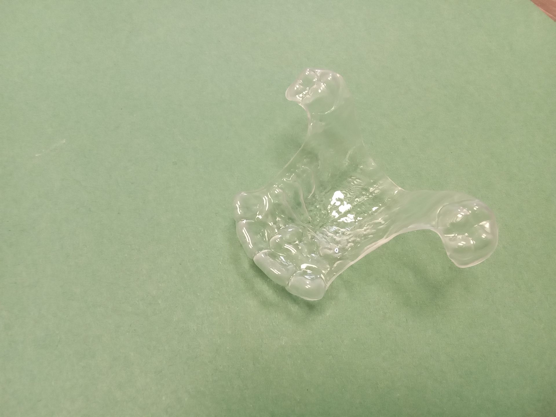 A clear plastic object is sitting on a green surface.