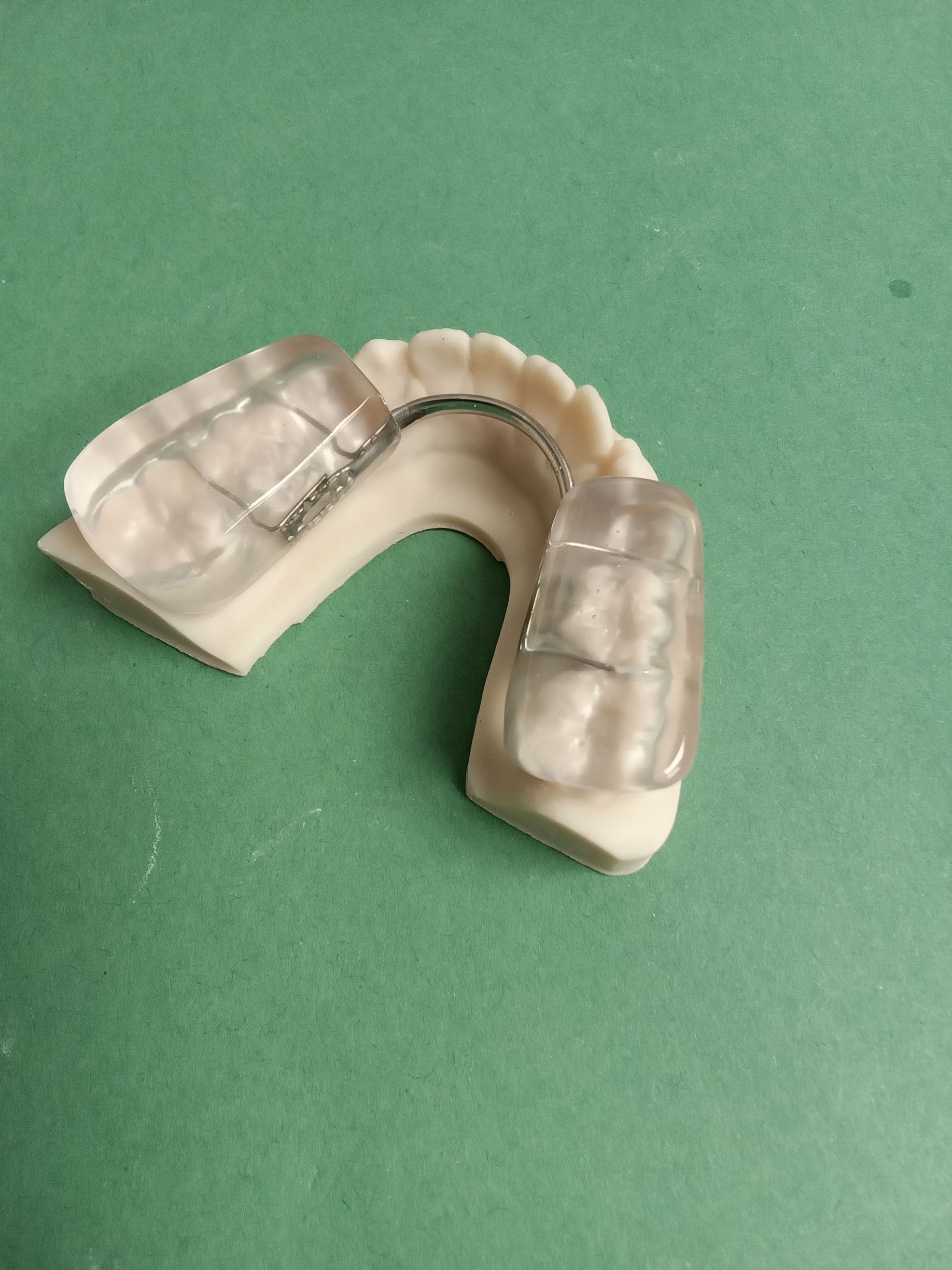 A close up of a mouth guard on a green surface.