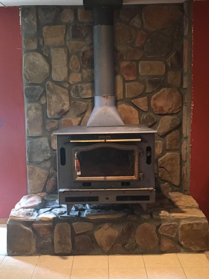 A stone fireplace with a wood stove in it