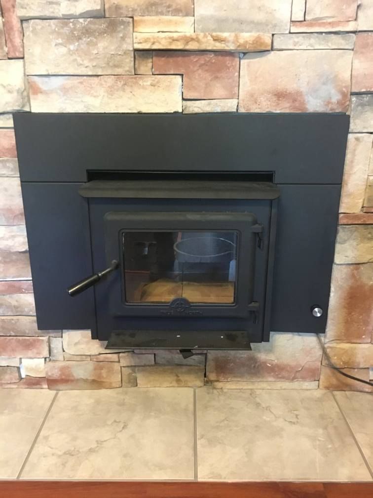 A wood stove is built into a stone wall.