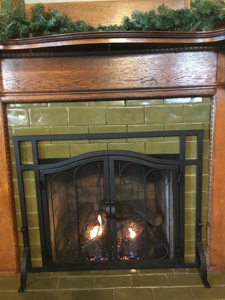 A fireplace with green tiles and a black screen