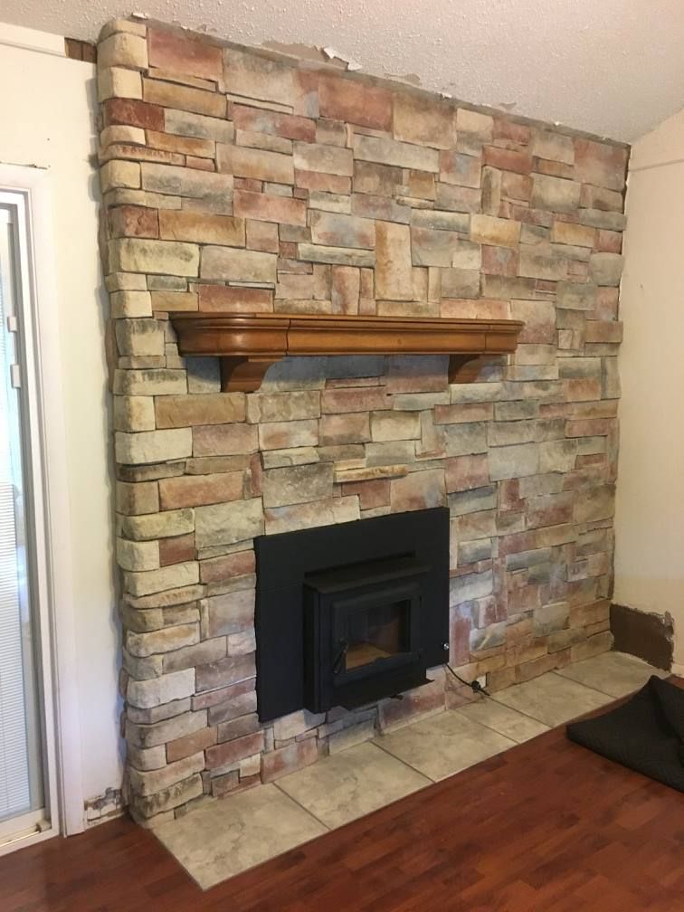 A living room with a fireplace and a stone wall.