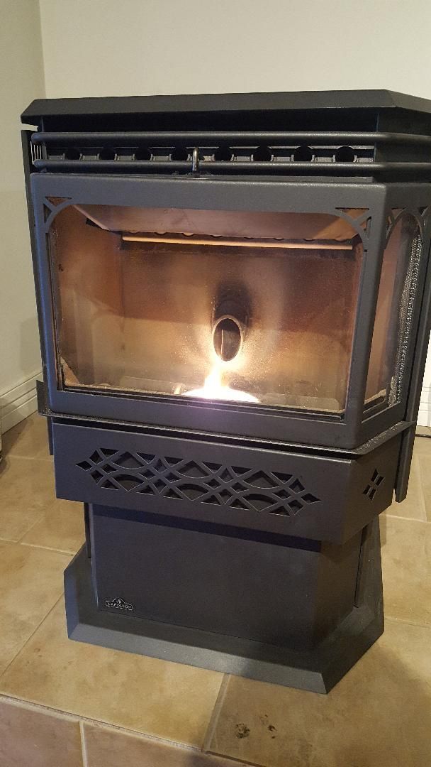 A black wood stove is sitting on a tiled floor in a room.