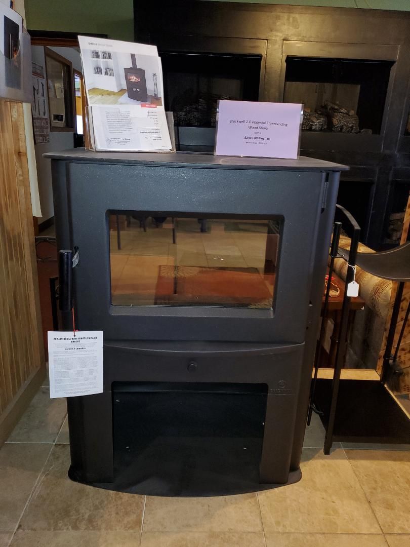 A black wood stove is sitting on a tiled floor in a room.
