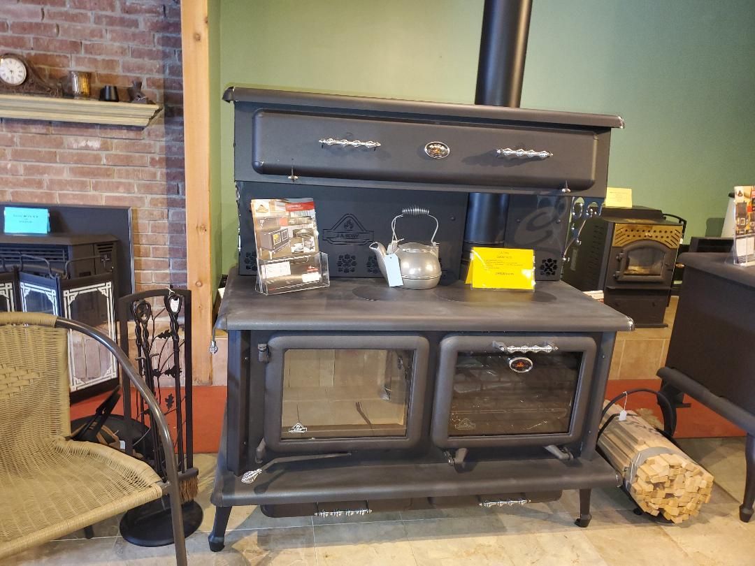 A black wood stove with a kettle on top of it