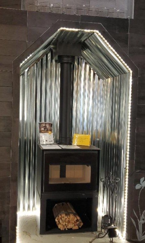 A wood stove is sitting in a corner of a room.