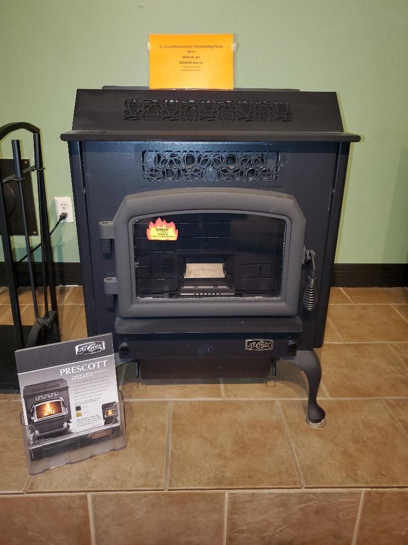 A black wood stove is sitting on a tiled floor next to a brochure.