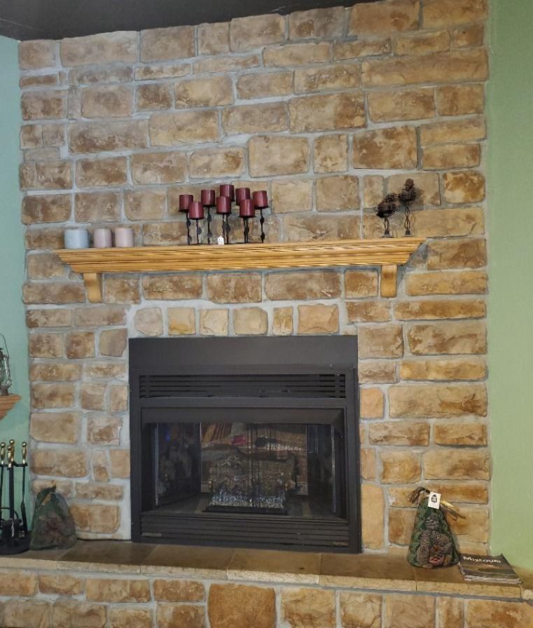 A brick fireplace with a wooden mantle and candles on it