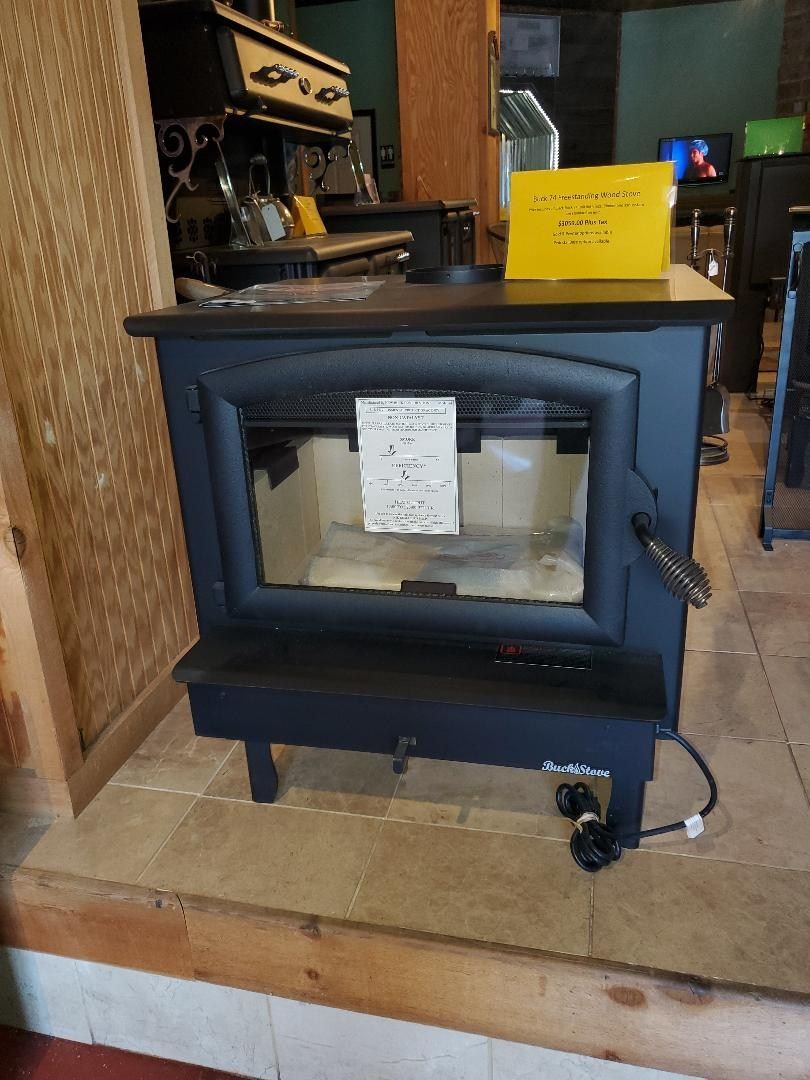 A black wood stove is sitting on a tiled floor in a room.