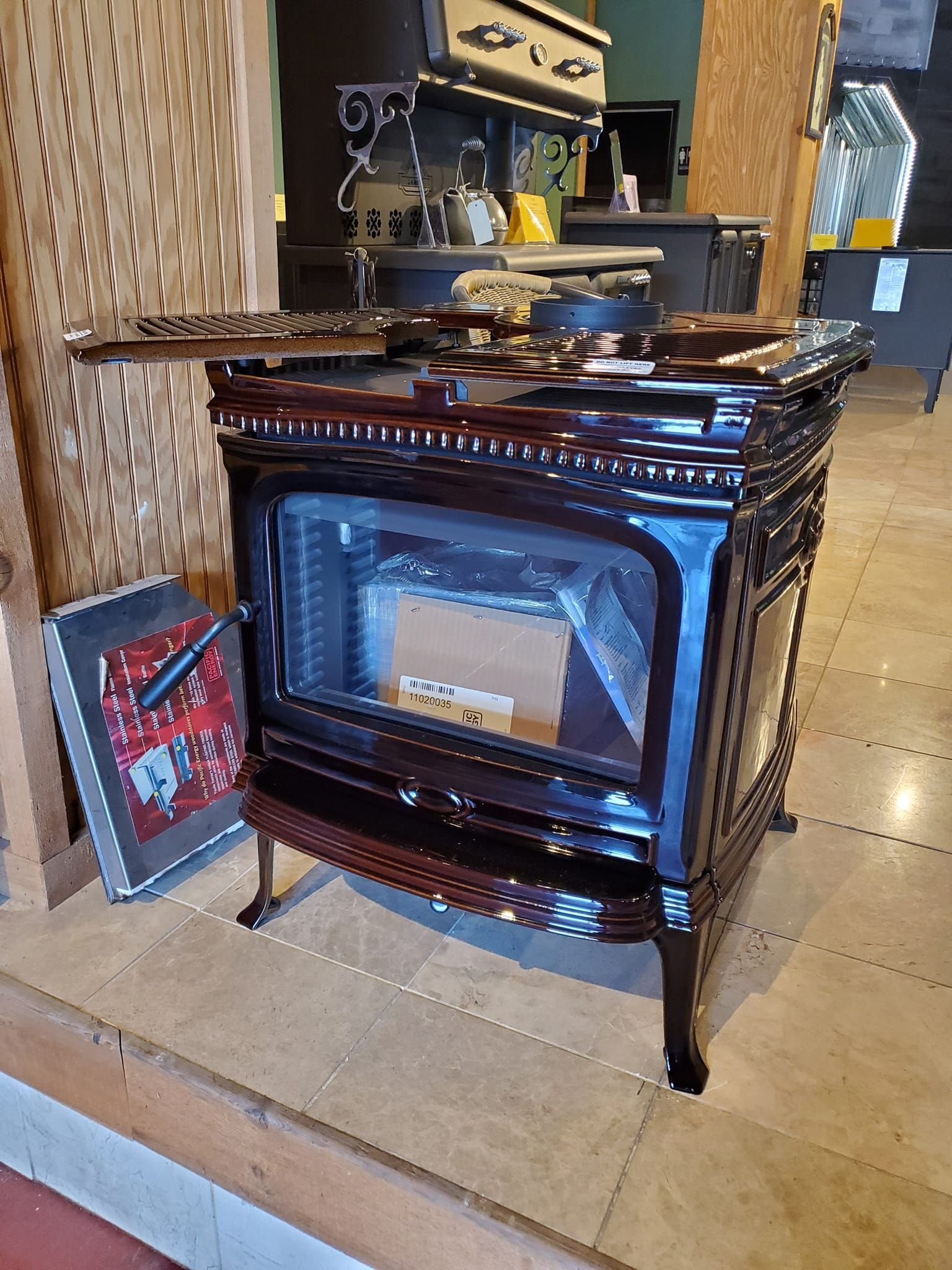 A wood stove is sitting on a tiled floor in a kitchen.