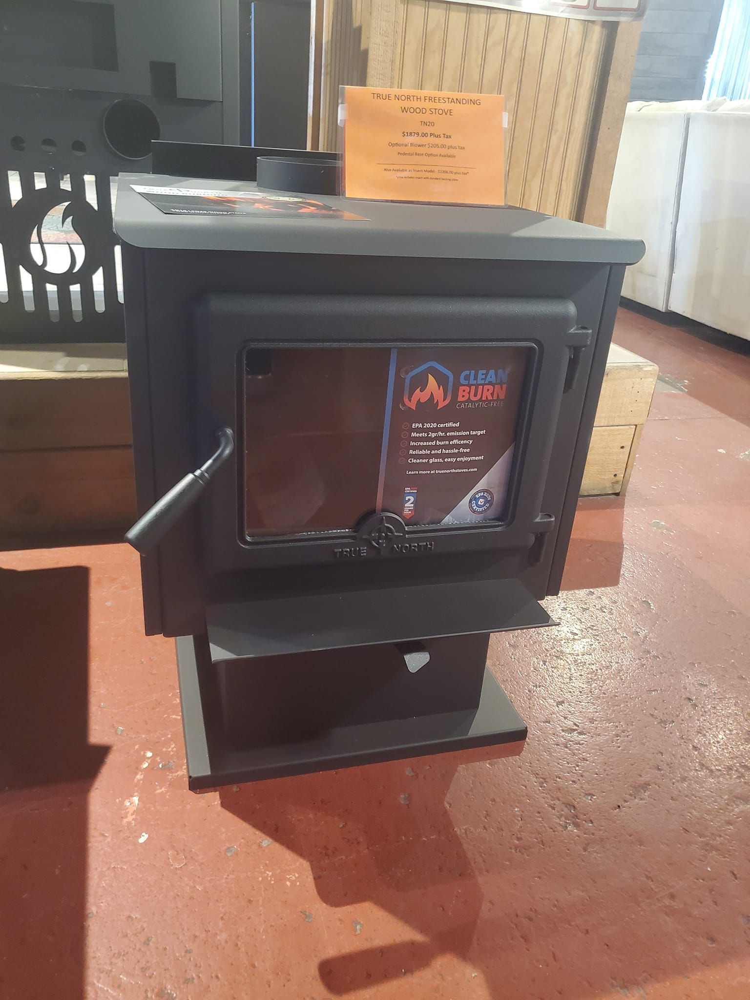 A wood stove is sitting on a red floor in a room.