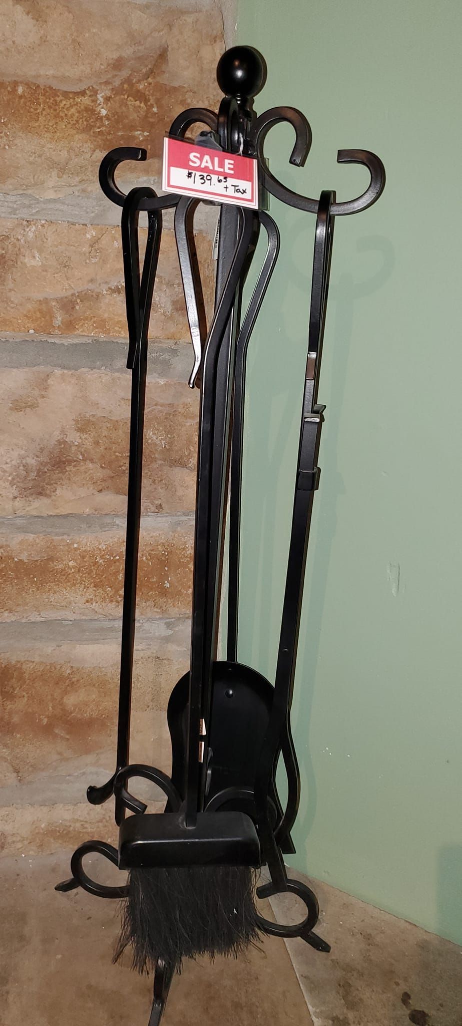 A wrought iron fireplace tool set is sitting in the corner of a room.