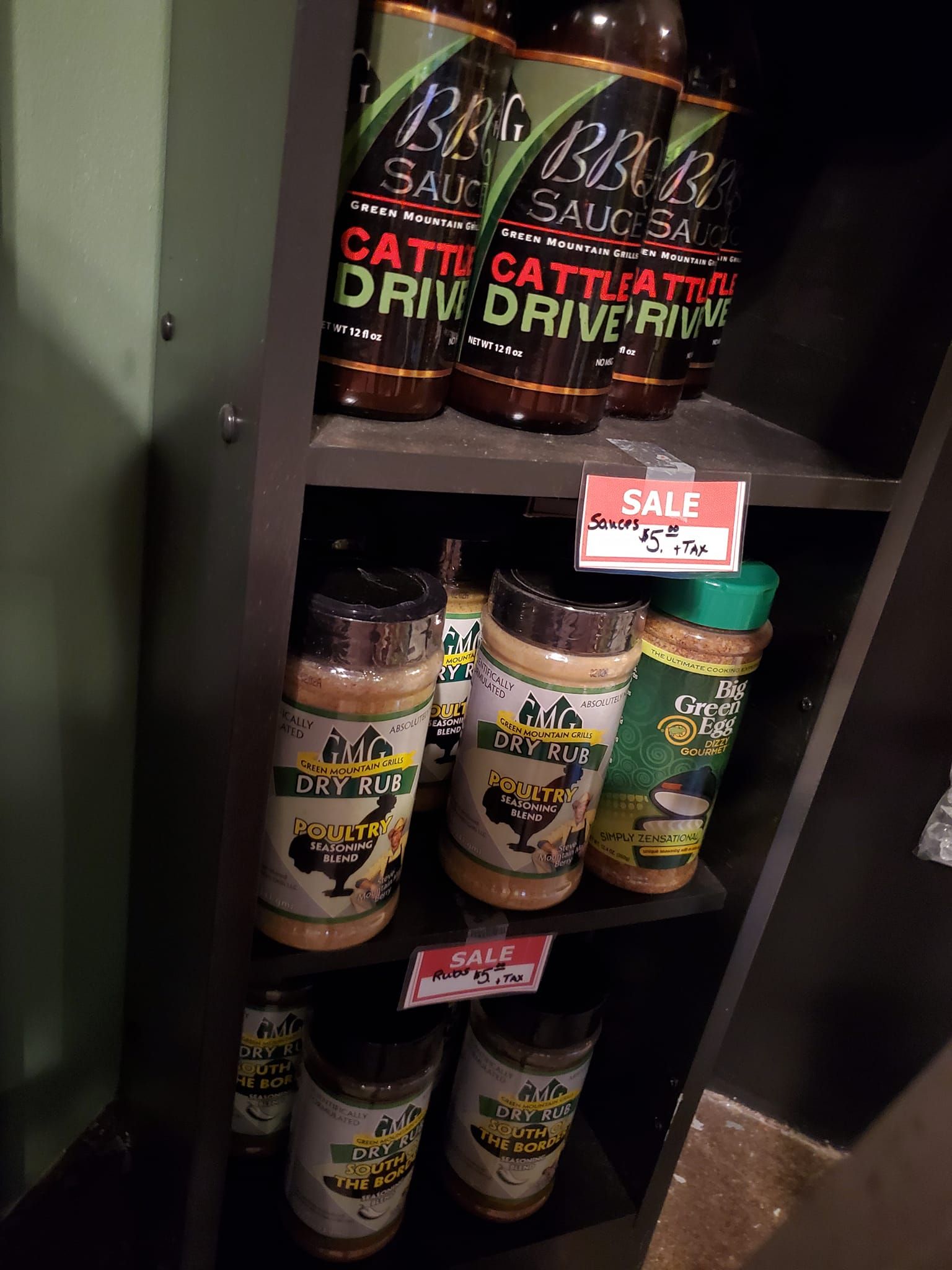 A shelf filled with bottles of sauce and a sign that says `` sale ''.
