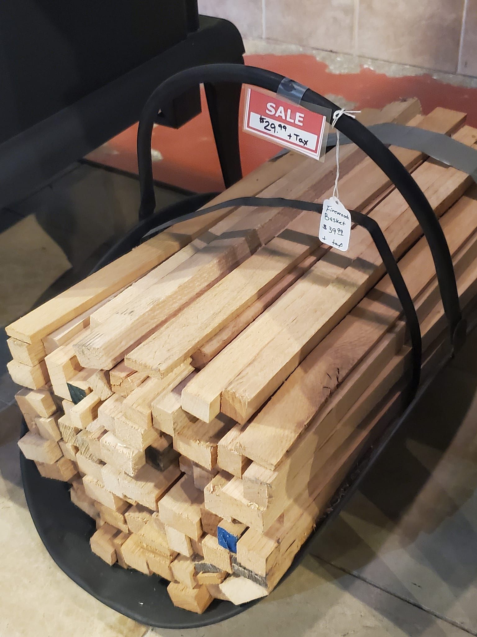 A pile of wood in a metal basket with a sale sign on it.