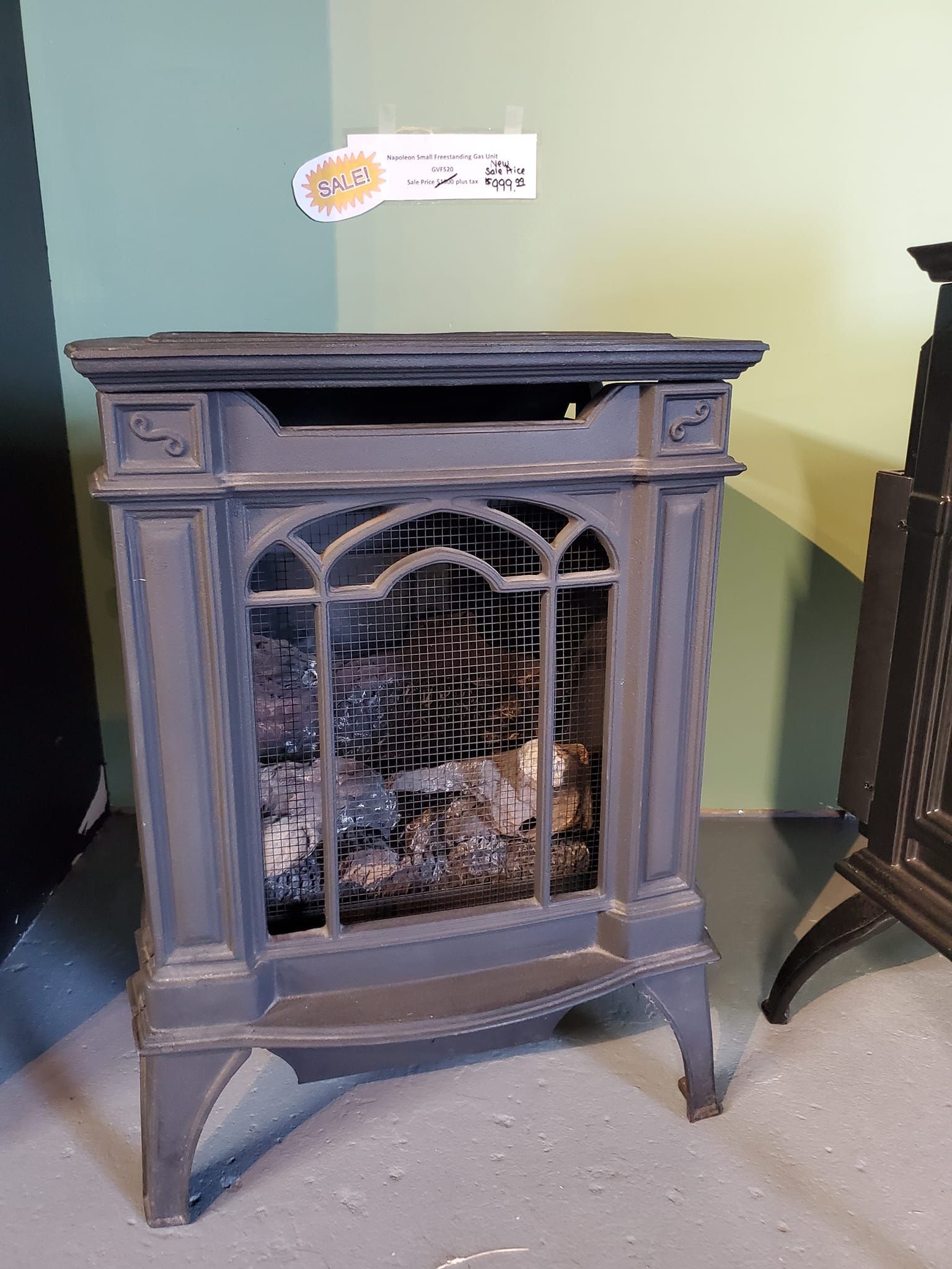 A wood stove is sitting in a corner of a room.