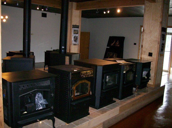 A row of wood stoves are lined up in a room