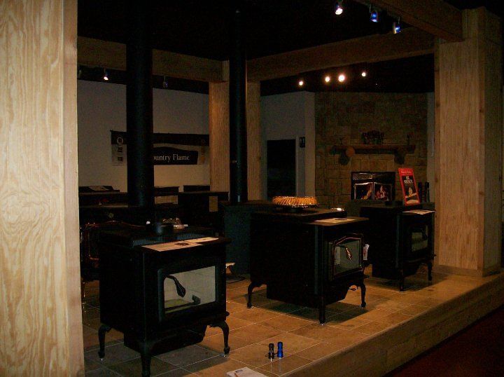 A display of wood stoves in a room with a sign that says ' stove ' on it