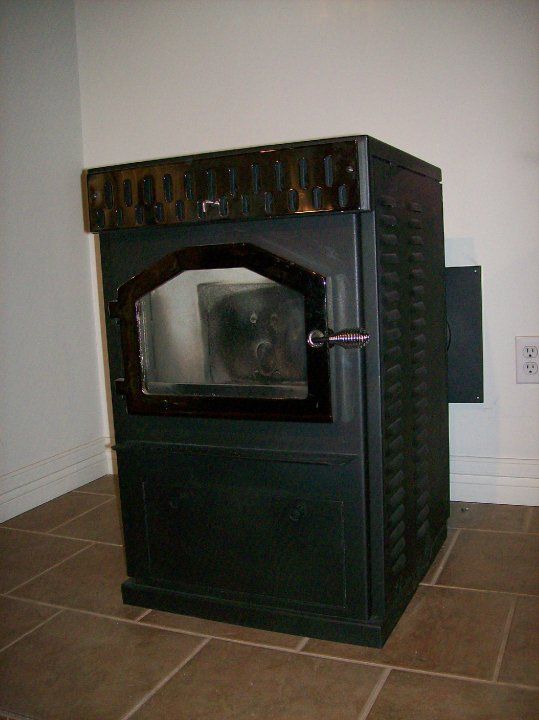 A black wood stove is sitting on a tiled floor in a room.
