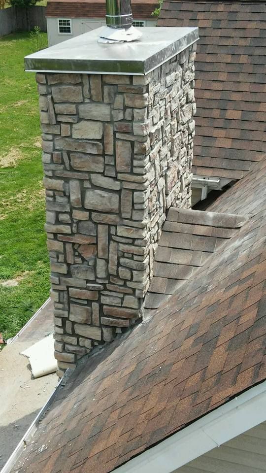 A stone chimney is on the roof of a house.