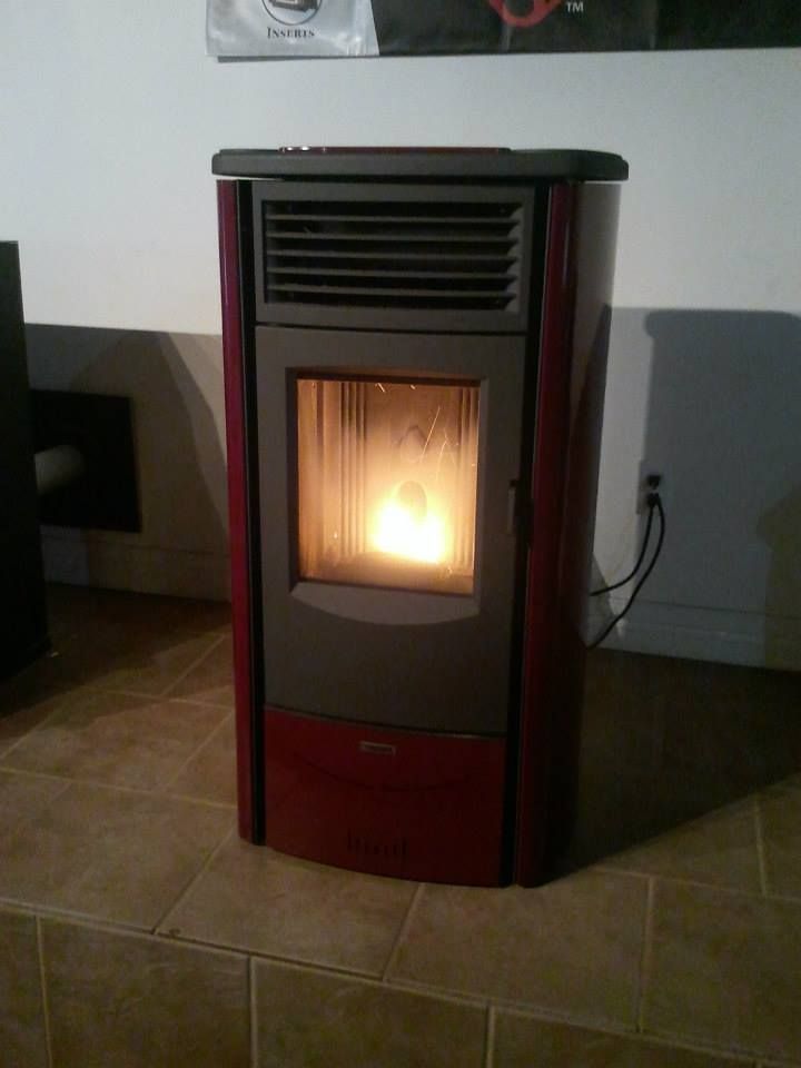 A red pellet stove is sitting on a tiled floor