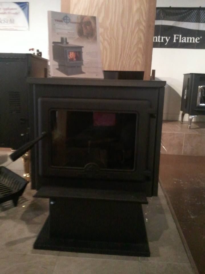 A wood stove is displayed in front of a sign that says country flame