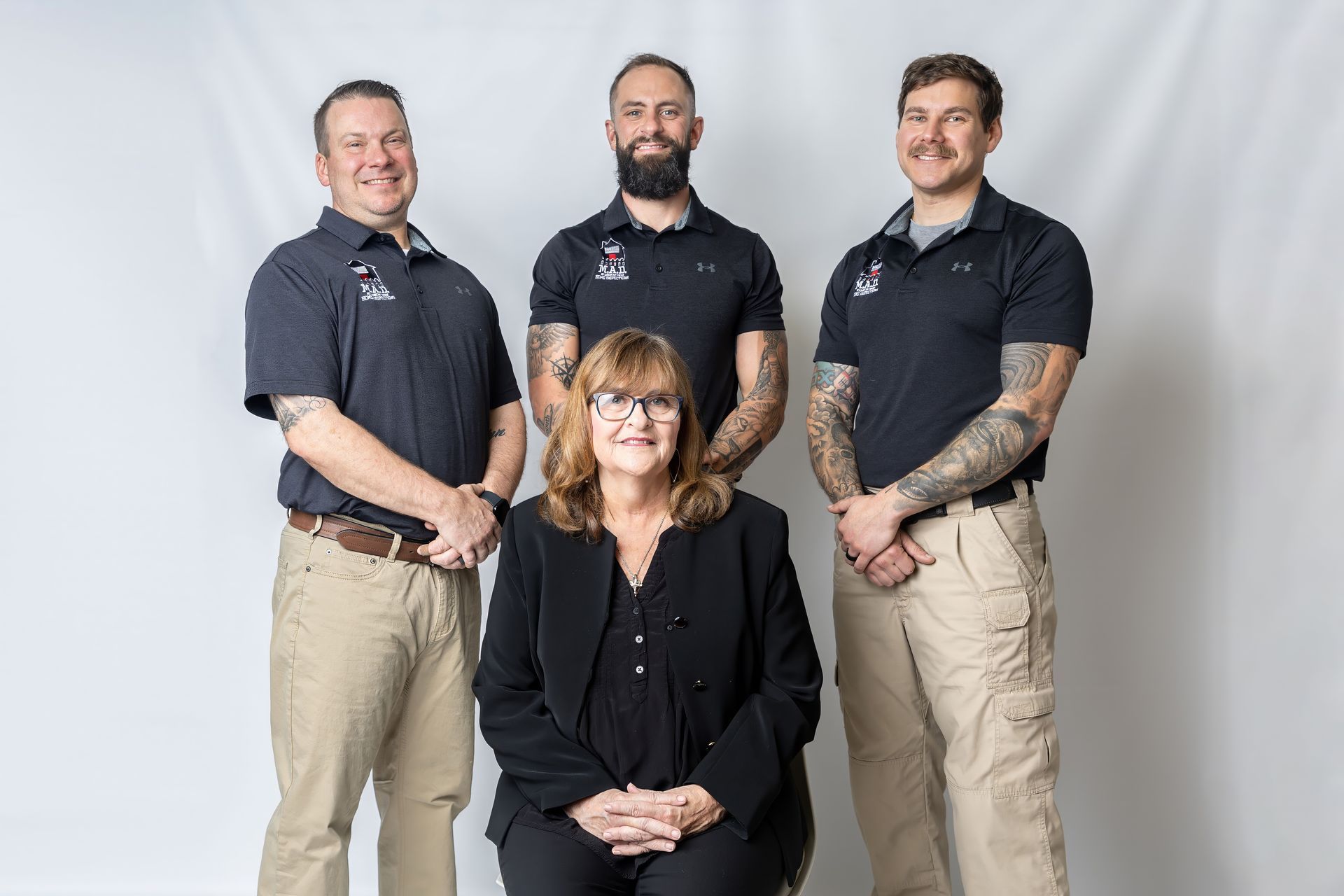 Five people in black polos and khaki pants posing against a white backdrop