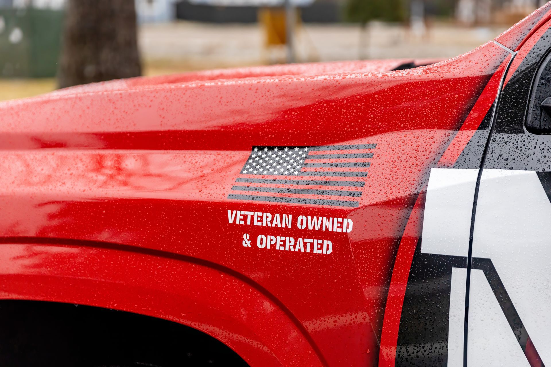Red vehicle door with American flag decal and “Veteran owned & operated” text on the side