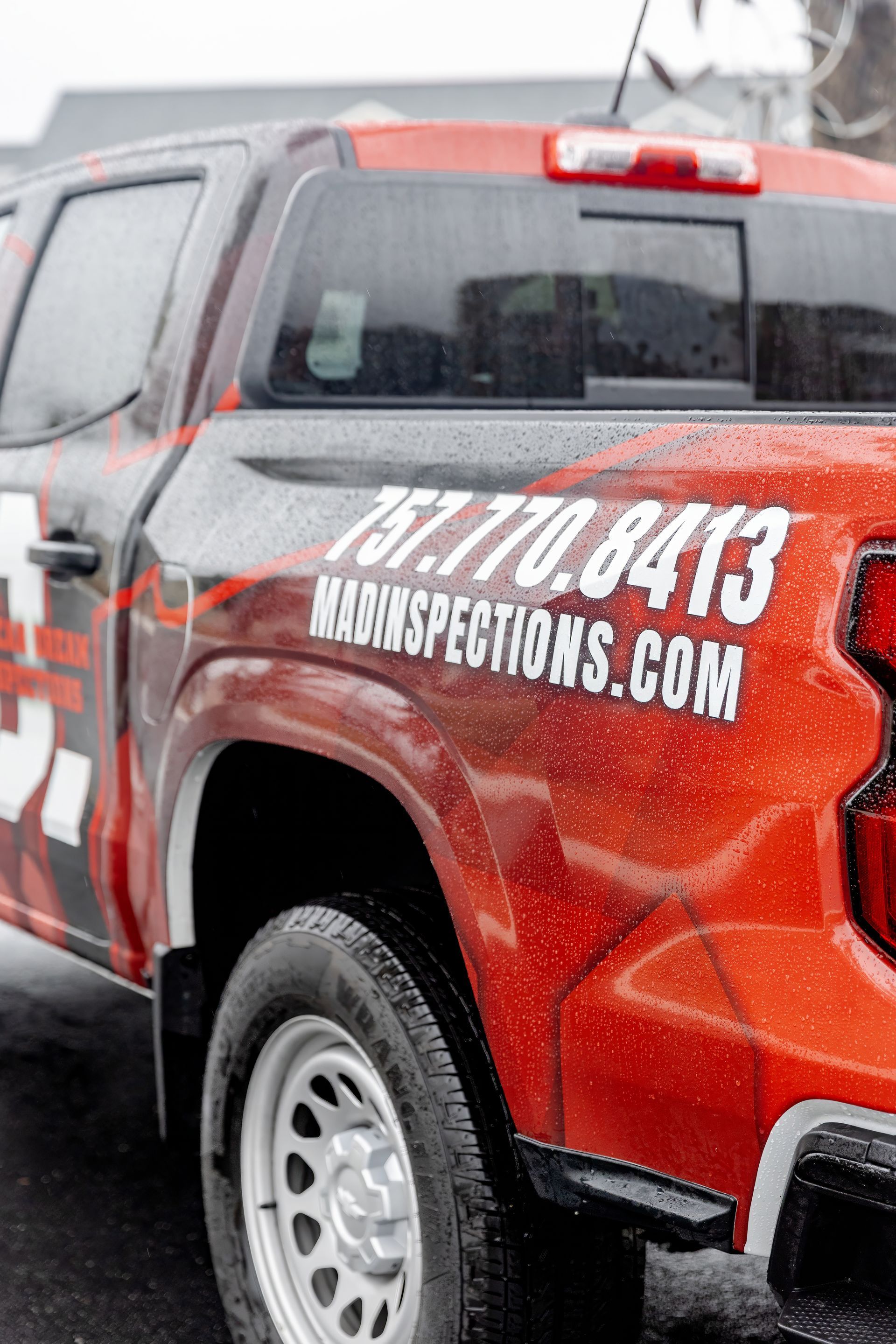 Red pickup truck with KINGCONCEPTS.COM and 317-770-8413 on the side in snowy weather