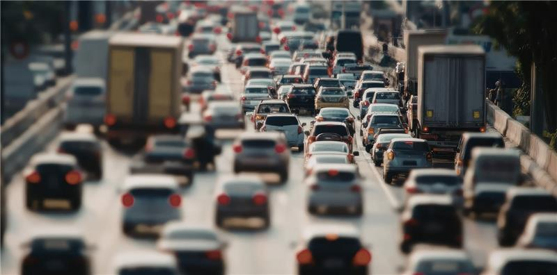 Heavy traffic on a multi-lane highway, with many cars and trucks packed closely together in a congested commute.