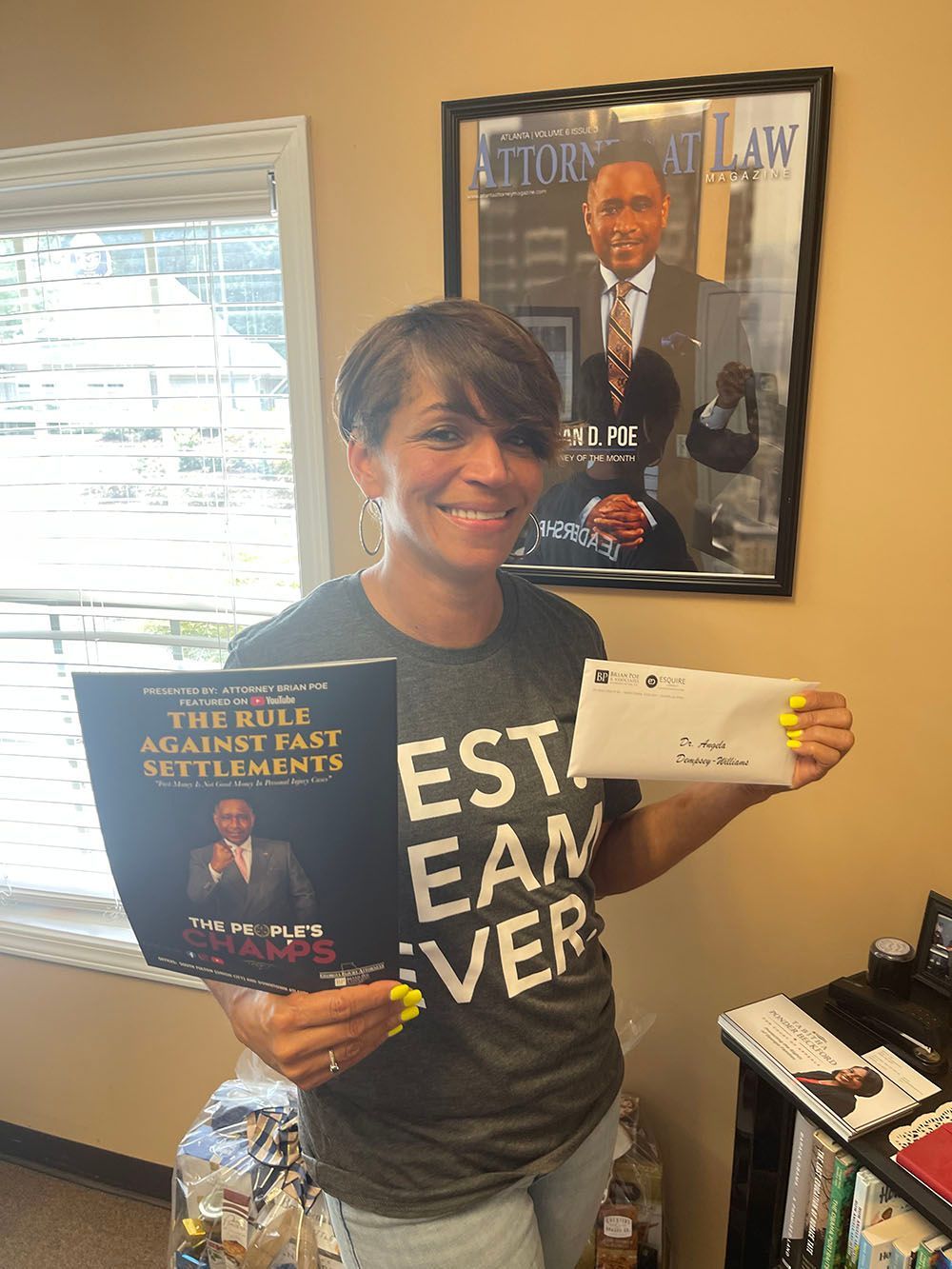 A woman wearing a shirt holding a book and an envelope